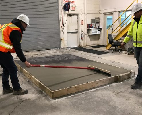 Dufferin Concrete employee demonstrating a Broom Finish on a sample concrete slab during the customer demo day
