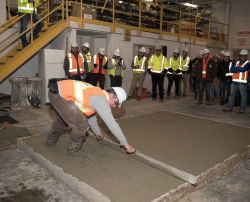 Duferin Concrete employee demonstrating how to Properly Place concrete on a sample concrete slab during demo day