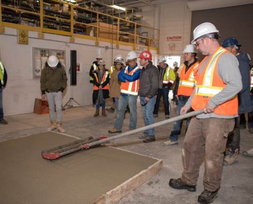 Dufferin Concrete employee demonstrating the use of a Roller Tamper (Jitterbug Roller) on a sample concrete slab